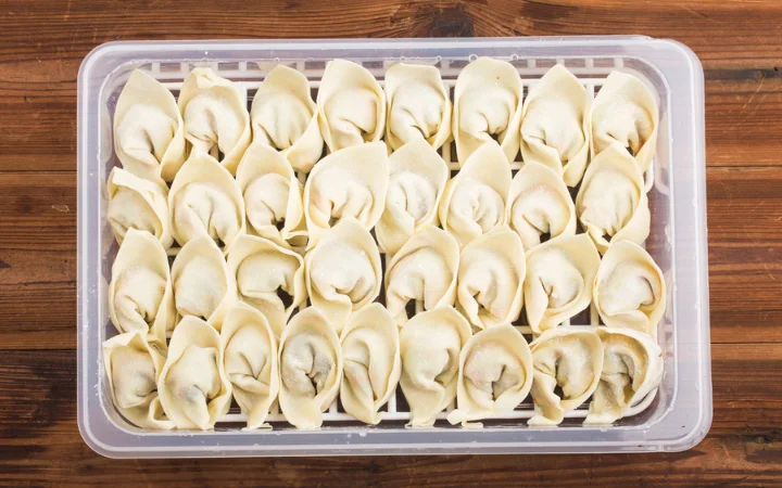 Homemade fresh wonton dumpling in acontainer ready to be stored.